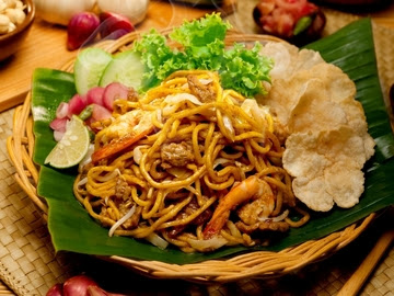 Mie Aceh goreng spesial dengan udang dan kerupuk di atas daun pisang